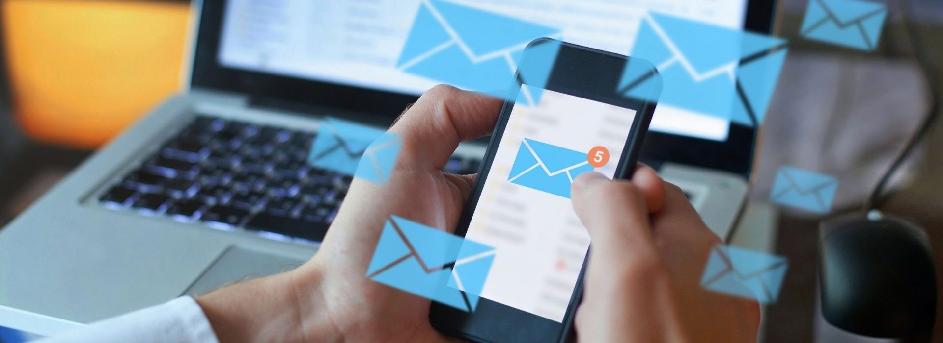 Enveloppes symbolisant des emails flottant au-dessus d'un ordinateur et d'un smartphone