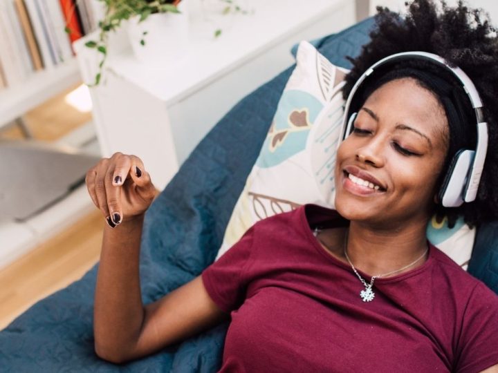 Femme allongée dans un canapé avec un casque sur les oreilles