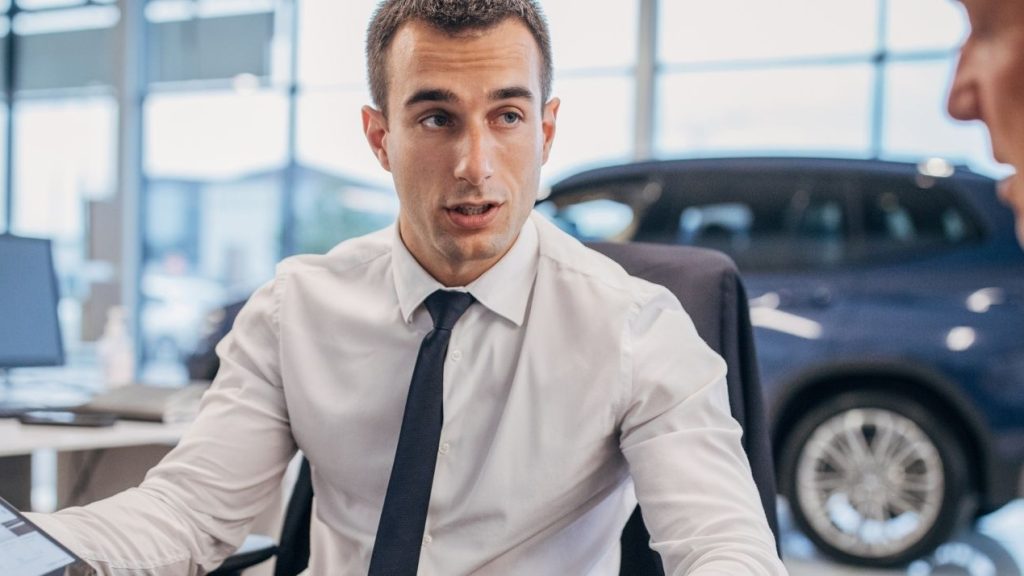 Vendeur parlant à un client dans une concession automobile