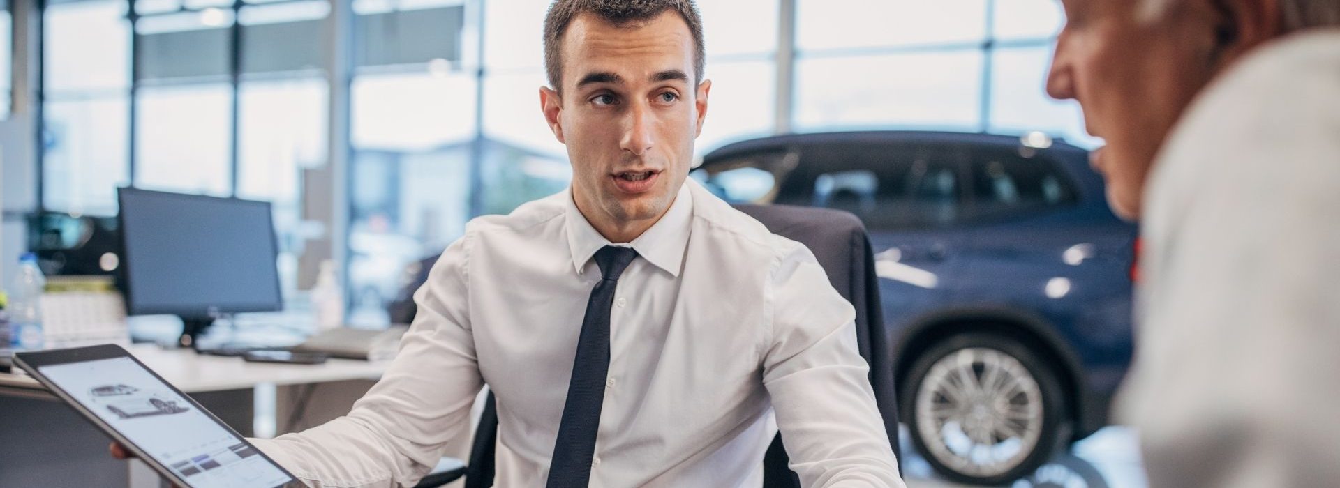 Vendeur parlant à un client dans une concession automobile
