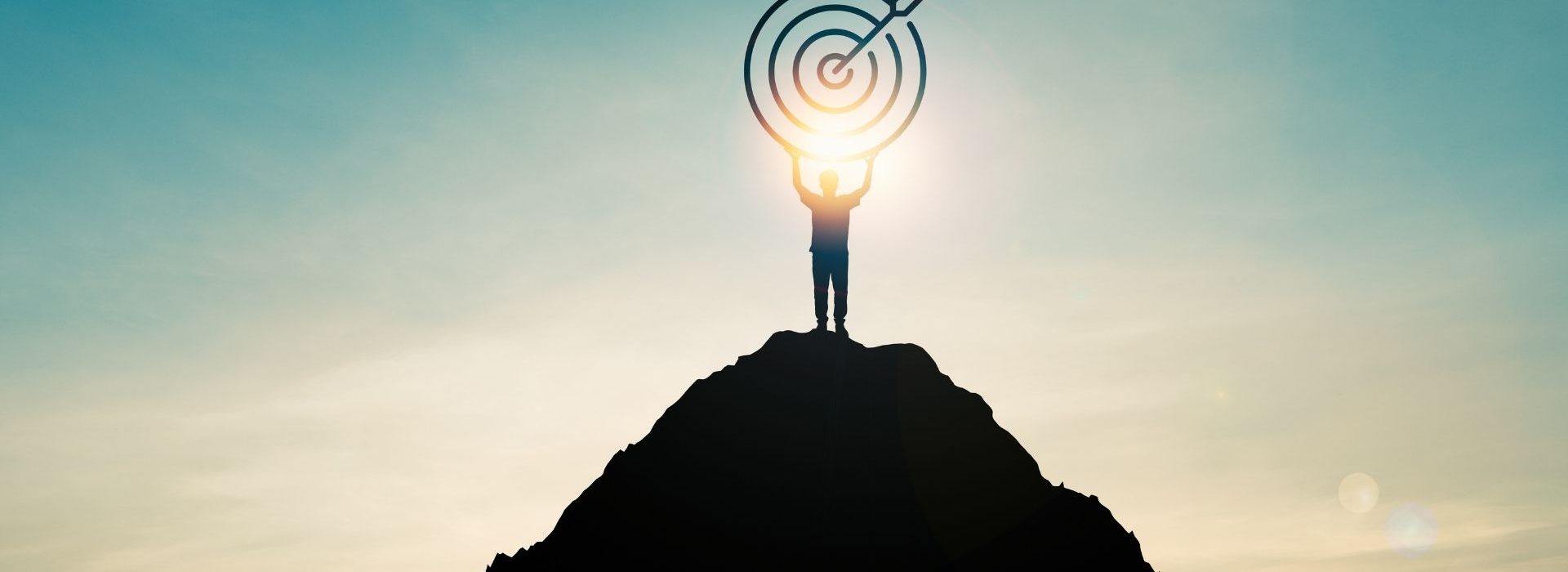 Durant votre prospection, vous devrez identifier tous les rôles qui entreront en jeu dans votre cycle de vente. Un homme tient une cible au sommet d'une montagne, avec le soleil à contrejour