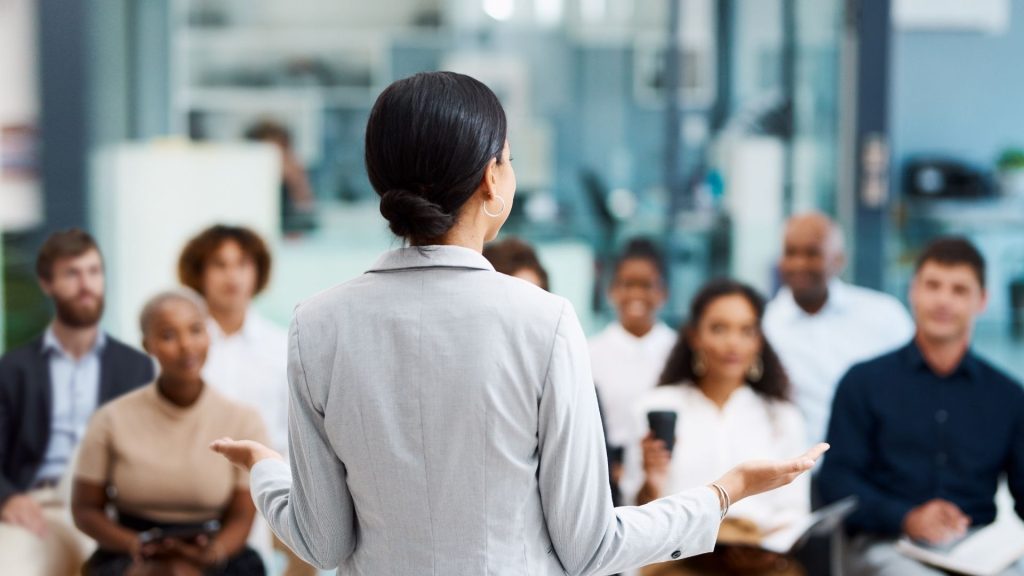 Quelles solutions peuvent apporter dirigeants et managers pour redonner du sens à leurs collaborateurs ? femme faisaint un disocurs devant un groupe de personnes