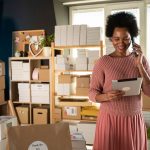Jeune femme entourée de cartons prêt à etre expédié dans sa boutique