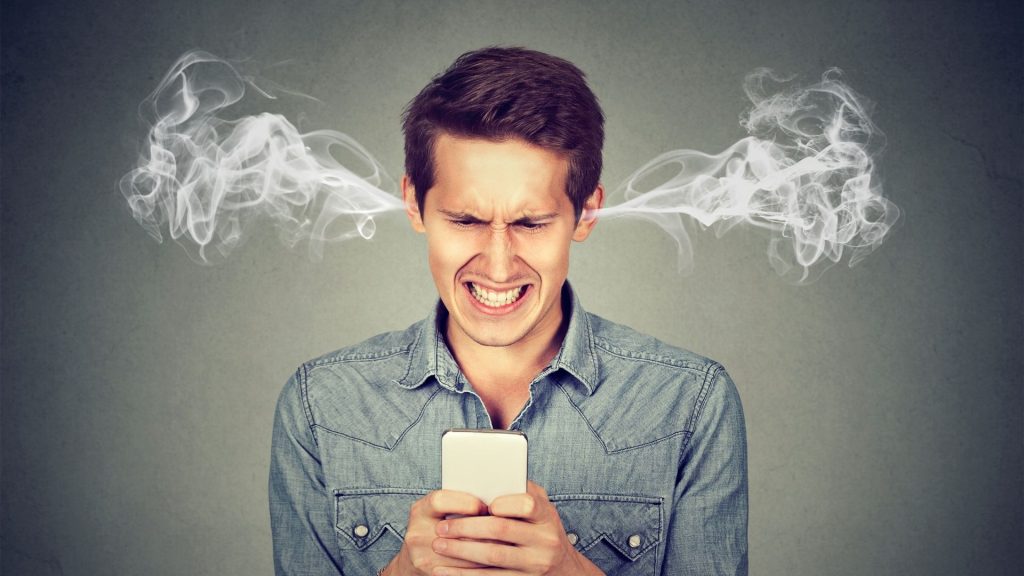 Homme en colère frustré, lire un message texte sur son smartphone souffle vapeur sortant des oreilles