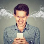 Homme en colère frustré, lire un message texte sur son smartphone souffle vapeur sortant des oreilles