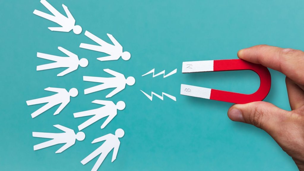 Du marketing à la pratique commerciale, le referral est un canal d’acquisition qui peut s’avérer redoutable s’il est bien exploité. Main attirant des figures humaines avec l'aimant de fer à cheval