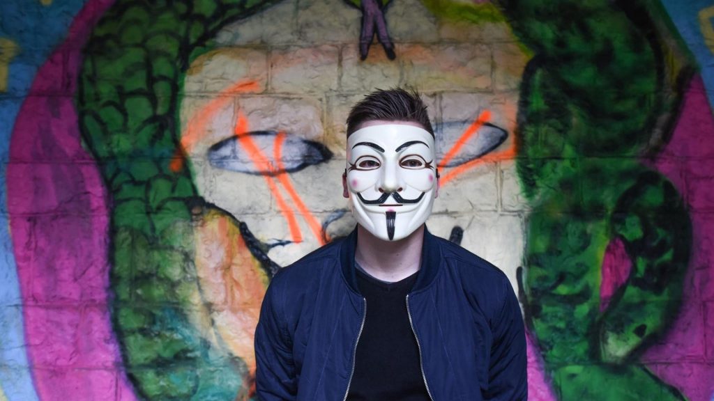 Homme avec un masque devant une fresque