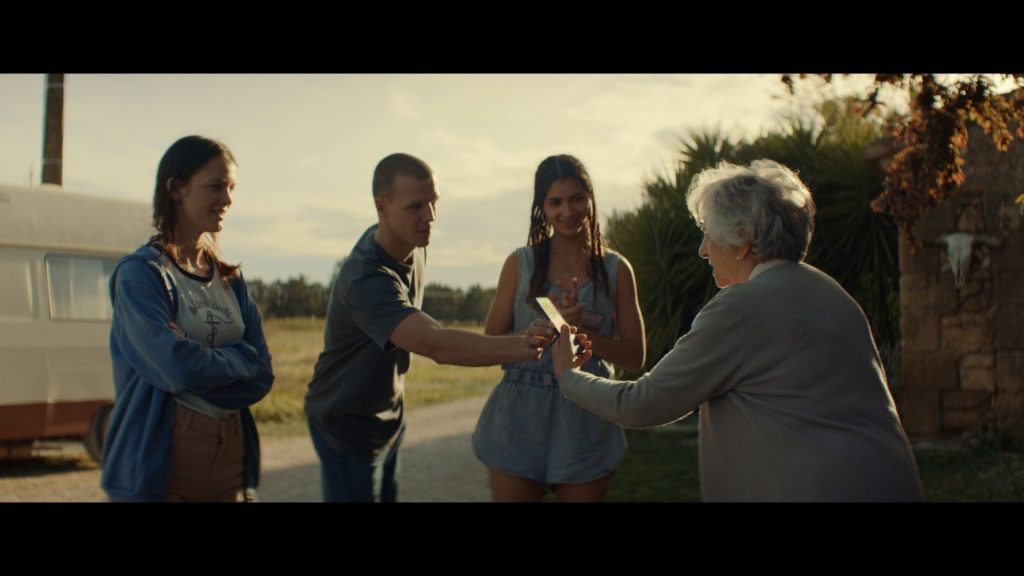 3 jeuens gens tendant un telephone à une personne âgée