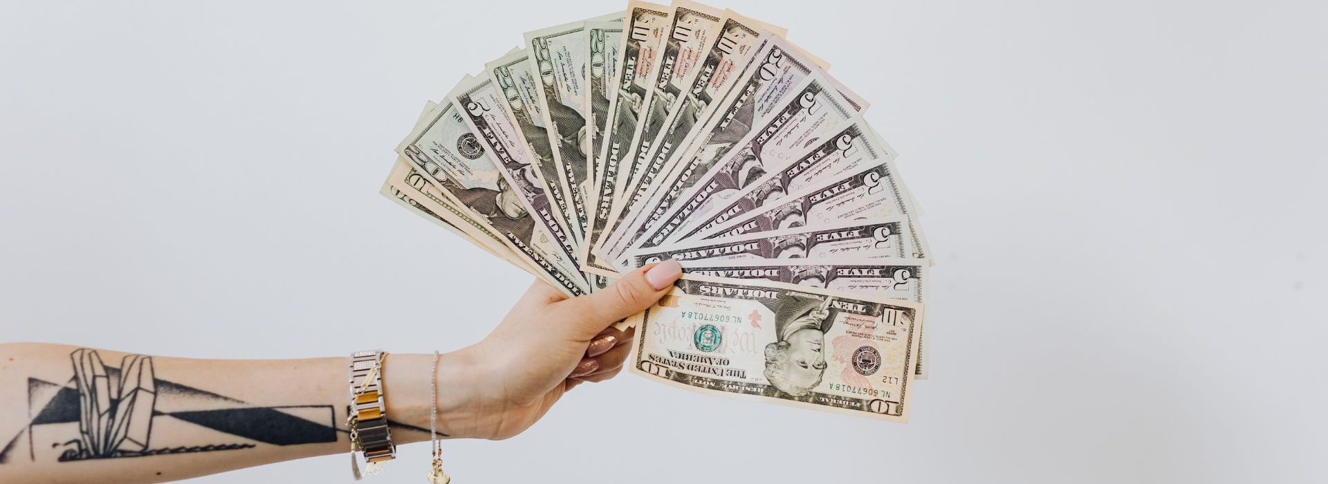 Comment établir une vraie stratégie autour de sa levée de fonds ? Bras tatoué tenant des billets