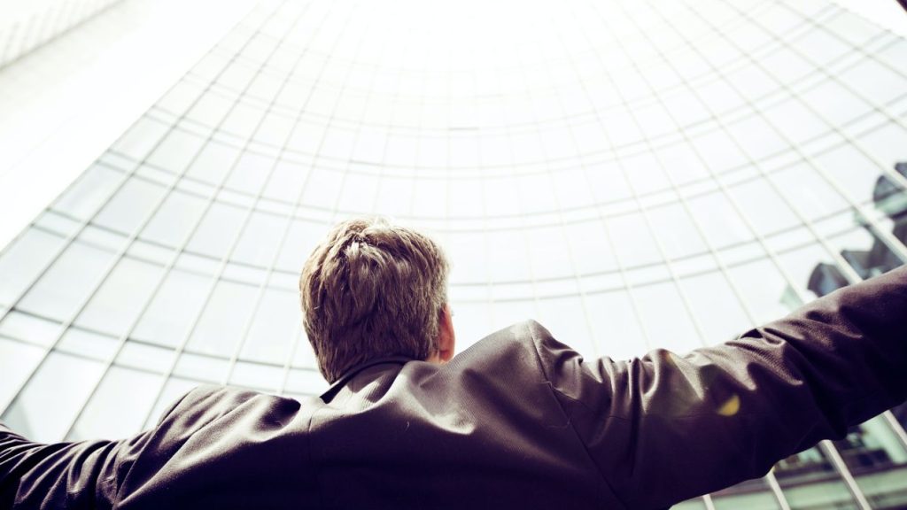 Top des métiers les plus recherchés dans le secteur de la Communication Homme levant les bras au ciel devant un building