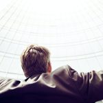 Homme levant les bras au ciel devant un building