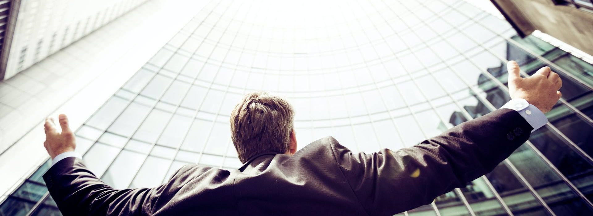 Top des métiers les plus recherchés dans le secteur de la Communication Homme levant les bras au ciel devant un building