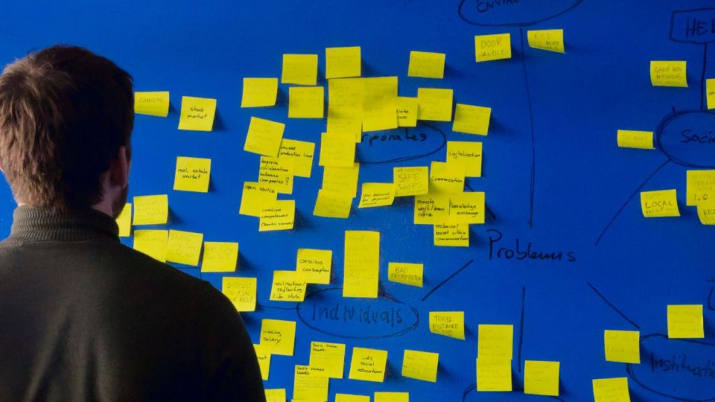 Qu'est-ce qu'une startup ? Hiomme devant un tableau rempli de post-it