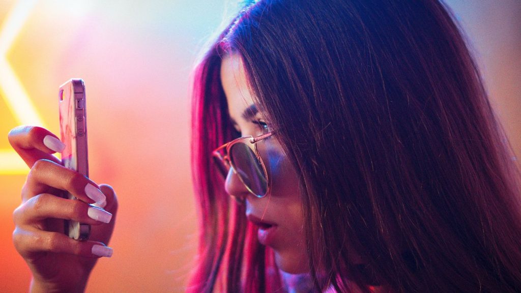 Etude : Hootsuite dévoile les principales tendances en matière de marketing sur les médias sociaux pour 2023 Jeune femme les yeux rivés sur son smartphone