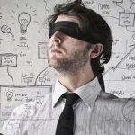 Hommes en costume cravate avec un bandeau sur les yeux devant un tableau de concepts