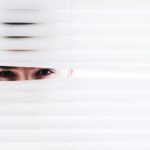 Personne regardant à travers des persiennes
