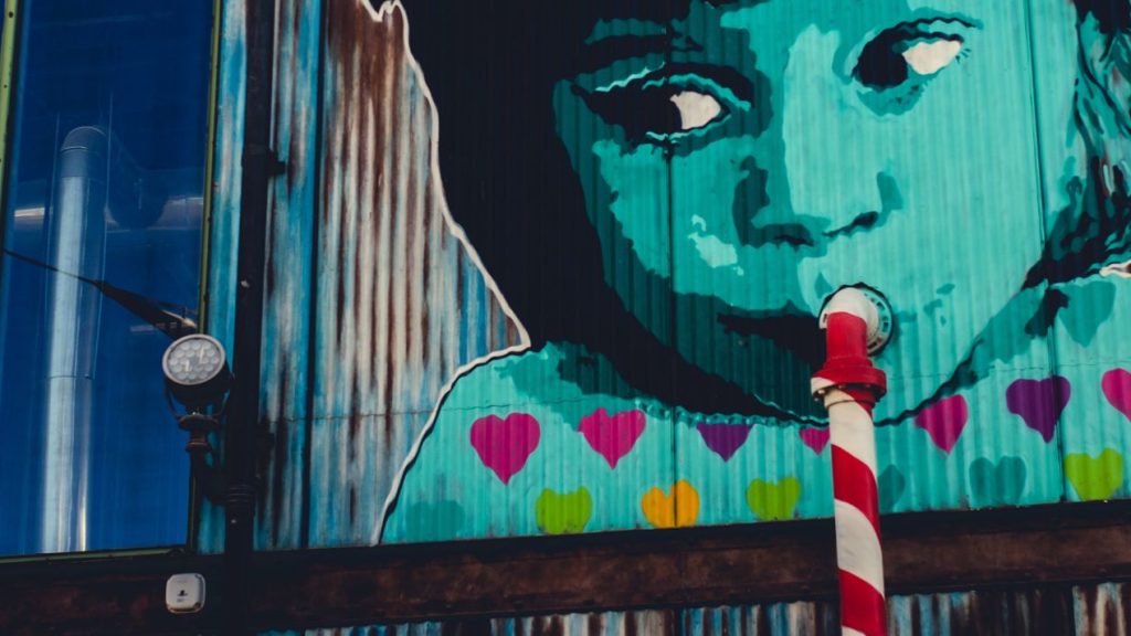 graffiti d'un enfant sirotant avec une paille dans la bouche, qui est un un tuyau de canalisation