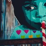 graffiti d'un enfant sirotant avec une paille dans la bouche, qui est un un tuyau de canalisation