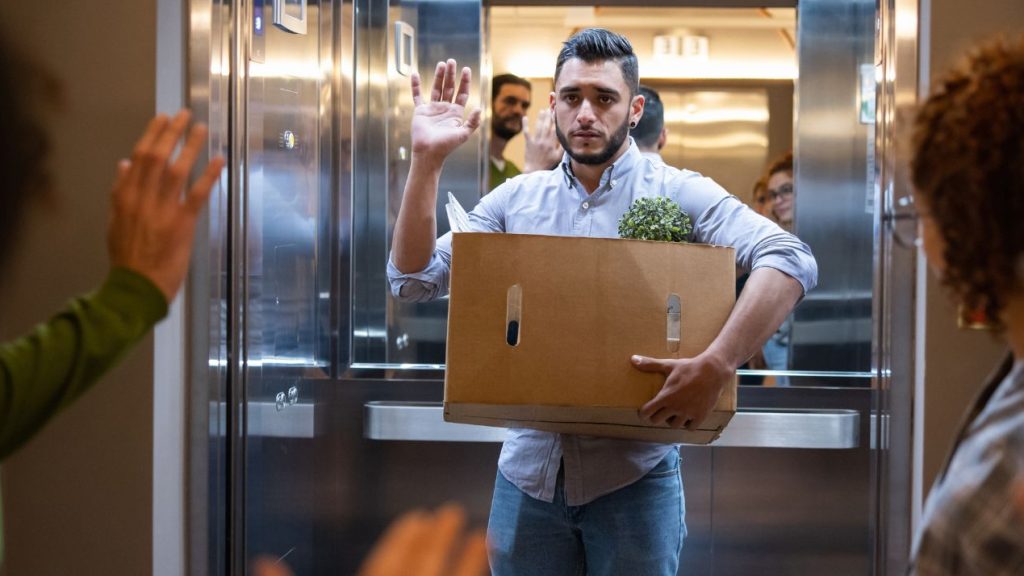 Homme dans un ascenseur avec un carton dans les bras