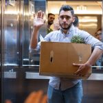 Homme dans un ascenseur avec un carton dans les bras