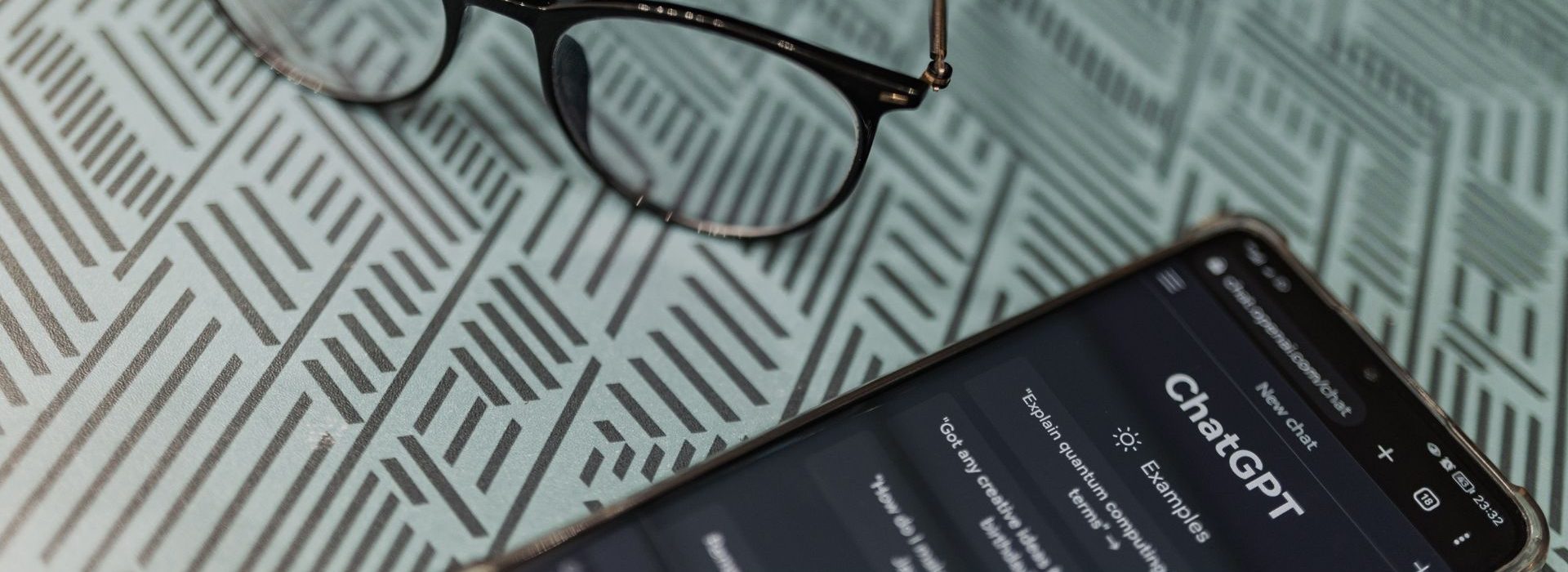 L'Académie du Newbiz lance une nouvelle formation : « Prompt Booster : l'art de briefer ChatGPT » Paire de lunettes à côté d'un téléphone portable sur l'appli ChatGPT